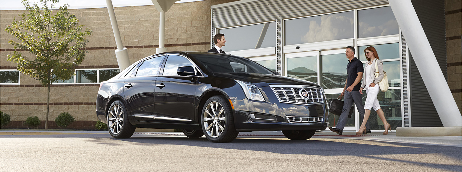 A sleek, black luxury vehicle parked in front of an airport.